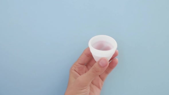 A Woman Holds a Menstrual Cup in Her Hands