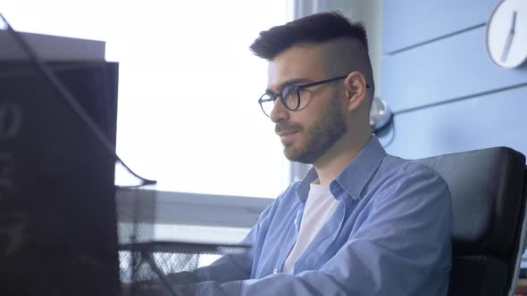 a young European male businessman works at a laptop computer in the office at home alt