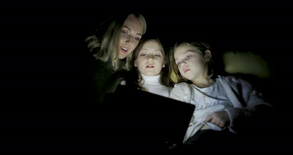 Woman and two girls using digital tablet at home to read ebook and remote lea