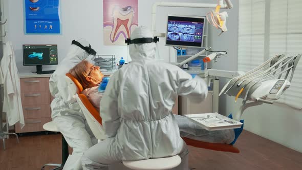 Nurse and Doctor in Protection Suit Working in Dental Unit alt