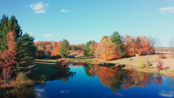 Aerial Drone Shot Ascending to Reveal a Pristine Farm Pond with Fall Colors