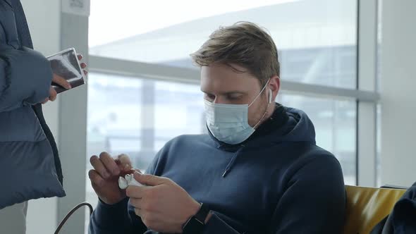 A Man Puts on Headphones and Talks to His Wife at the Airport During the Coronavirus Pandemic While