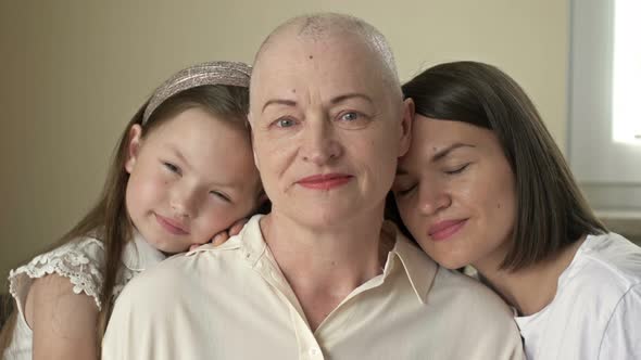 An Adult Daughter and Little Granddaughter Hug a Sad Elderly Woman Who Has Gone Bald After alt