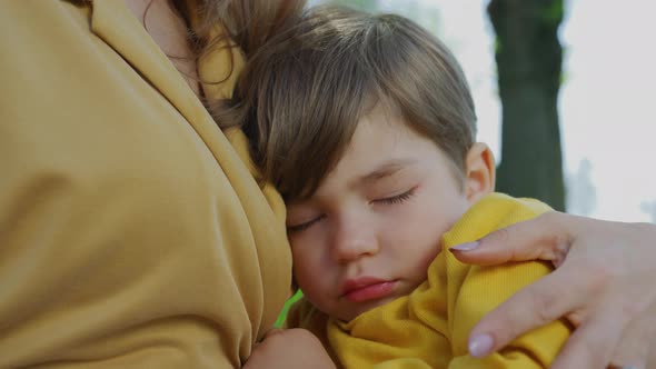 Child napping in the mother's arms alt