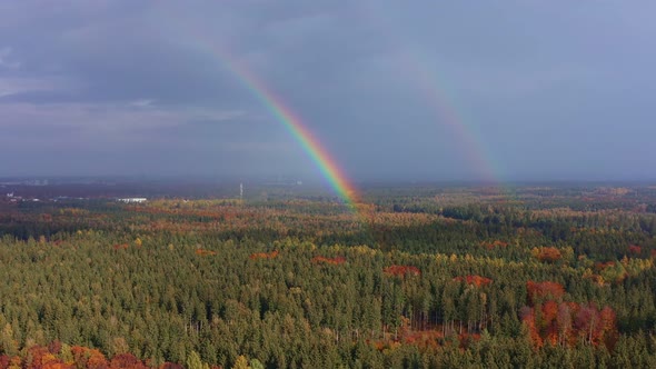 Aerial of a colorful double rainbow over an autumn forest. Flying by drone over a countryside full o alt