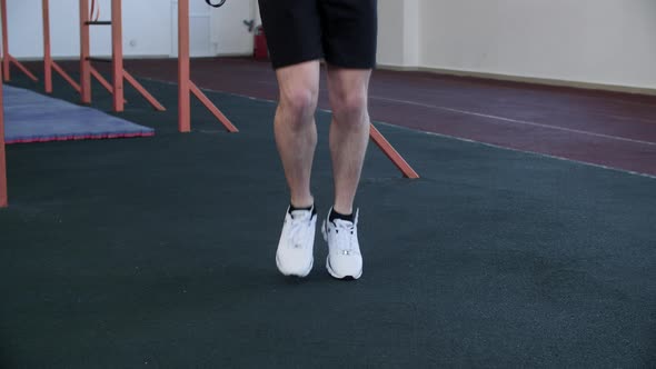 Legs of Man in Shorts Warming Before His Workout Skipping the Rope in Gym