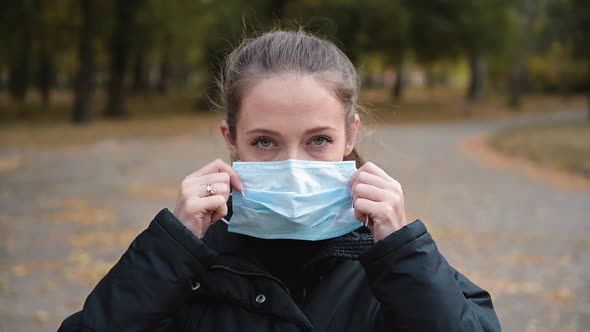 Woman Putting on Medical Mask for Coronavirus Protection Outdoors
