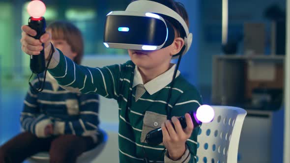 Little Boy in Vr Headset Playing Virtual Reality Game with Controllers While Another Boy Waiting for alt