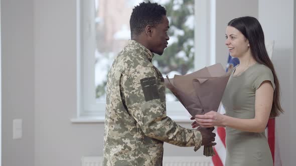 Surprised Young Wife Receiving Bouquet of Flowers From Husband and Hugging Spouse Smiling alt