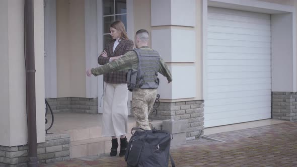 The Man in Military Closes with a Bag Comes Back Home and Meets His Wife in Front of House. The Lady alt