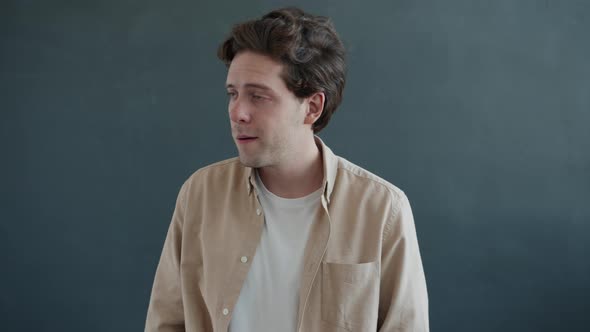 Portrait of Goodlooking Man Winking and Smiling Looking at Camera on Gray Color Background alt