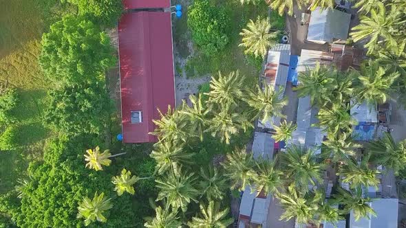 Aerial flight over local village huts and forest in Malaysia, birds eye perspective moving forward i alt