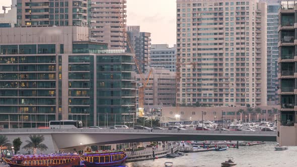 Yachts and Boats with Tourists Staying Near Shoping Mall and Passing Under a Bridge in Dubai Marina alt