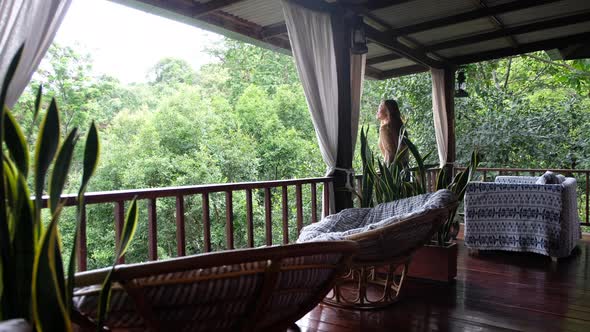 A young asian woman walking outside the room and looking at a beautiful view on balcony