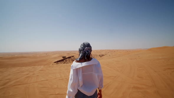 Young Caucasian Woman with Scarf and Sunglasses Walking Around Sand Dunes in the Desert alt