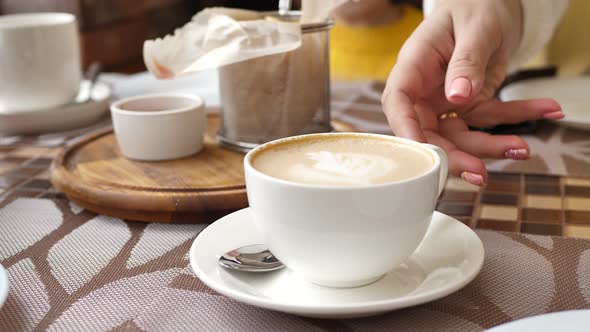 Cup of Coffee on the Table in a Cafe Which is Removed By a Woman's Hand