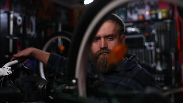 Tracking Shot of Experienced Repairman Watching Rear Shifter of Mountain Bike Changing Speeds Using alt