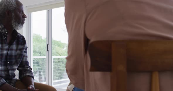 Two diverse senior couples sitting in circle having a therapy conversation at home alt