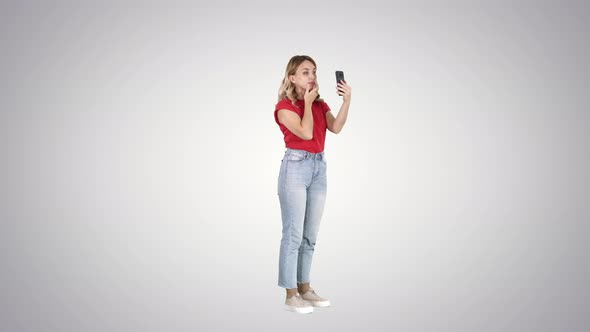 Blonde Woman Preening in Front of the Smartphone on Gradient Background. alt