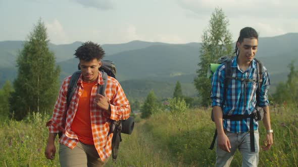Positive Multiracial Male Travelers with Backpacks Using Compass for Navigation on Mountain Hiking alt