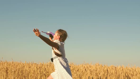 Happy Girl Runs with a Toy Airplane on a Field in the Sunset Light. Children Play Toy Airplane