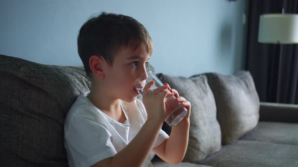 Cute Little Baby Boy Drinking a Glass of Water in Home alt