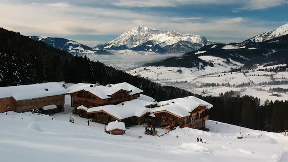 Aerial drone shot of a ski resort with wooden cabins in the Austrian mountains.