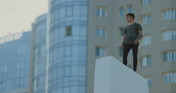 Young Man Stands on a High Place in the City. High-rise Buildings, Houses. alt