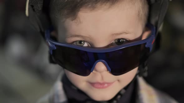 Cute Boy with Goggles Poses for Camera on Blurred Background