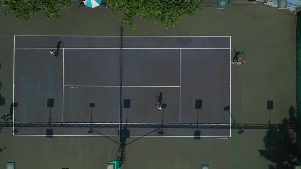 Aerial top down view of men's doubles tennis game showing full court. Serve is returned. Volley is h alt