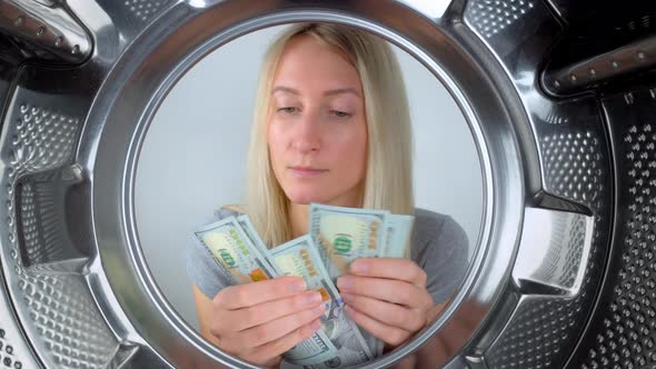 housewife counts money near washing machine and leaves them to wash. alt