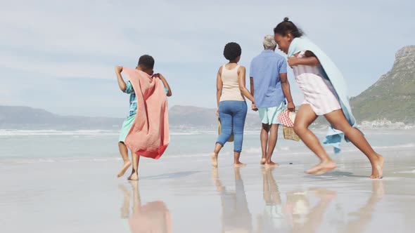 African american couple walking with children on sunny beach alt