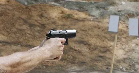 Slow motion of a hand gun firing in a firing range with cartridge flying away