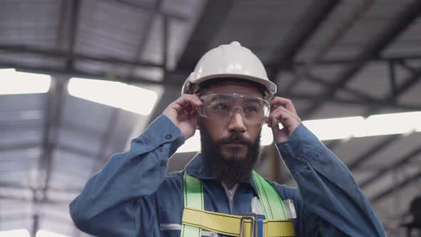 Male engineer in safety uniform wearing hardhat and protective eyeglasses