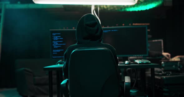 Shot From the Back to Hooded Hacker Breaking Into Corporate Data Servers From His Underground alt