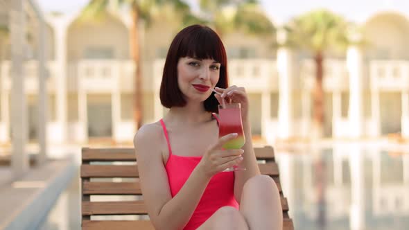 Portrait of Young Woman in Pink Bikini Swimsuit with Cocktail Glass Chilling in the Tropical Sun alt