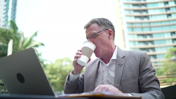 senior businessman working confident on a laptop, business person man working outside office in city alt