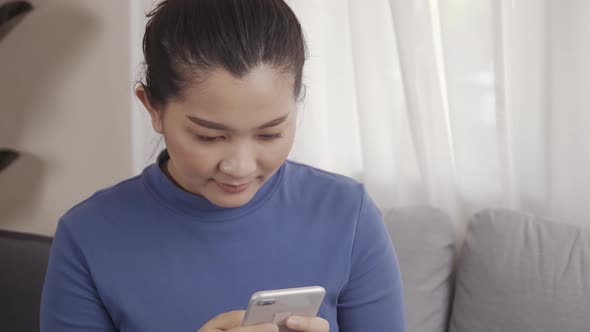 Asian woman on using a smartphone with AI voice command for a chat with customer alt