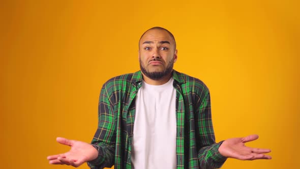 Clueless African American Man Gesturing He Doesn't Know Against Yellow Background alt