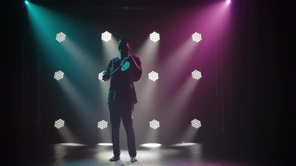 Silhouette of Musician Plays the African Talking Drum Yuka in a Dark Studio Against the Backdrop of alt