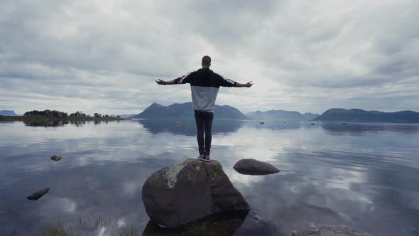 Man on rock in peaceful lake alt