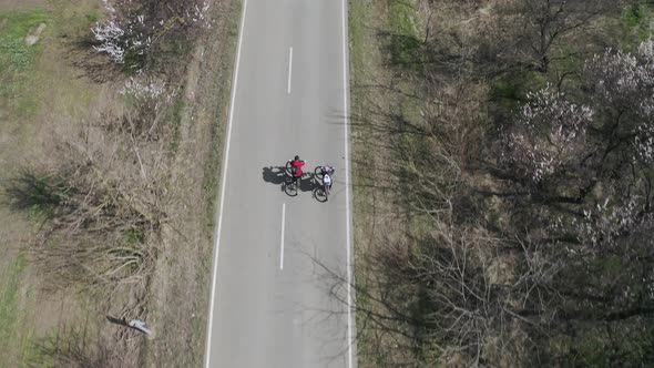 Aerial View of a Happy Couple of Cyclists Riding Along the Road alt
