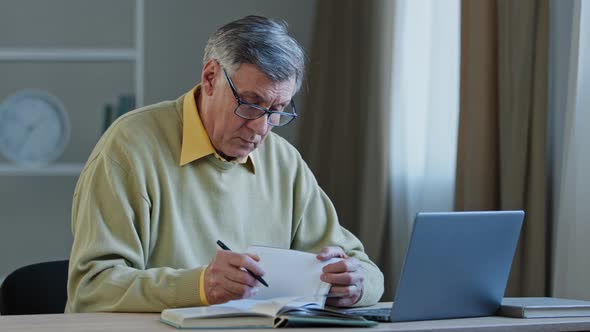 Multitasking Retired Caucasian Teacher Professor Senior Mature Man in Eyeglasses Looking at Laptop alt