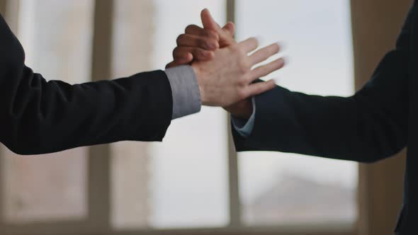 Closeup Male Workers in Formal Suits Making Unusual Funny Handshake Shaking Hands Informal Standing alt