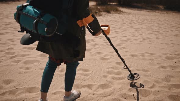 Unrecognizable Person Scanning the Sand with Metal Detector To Find Lost Precious Metals. alt