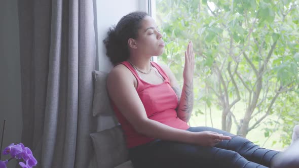 Cute African American Woman Sitting on the Window Sill Cutting Nails with a Nail File alt