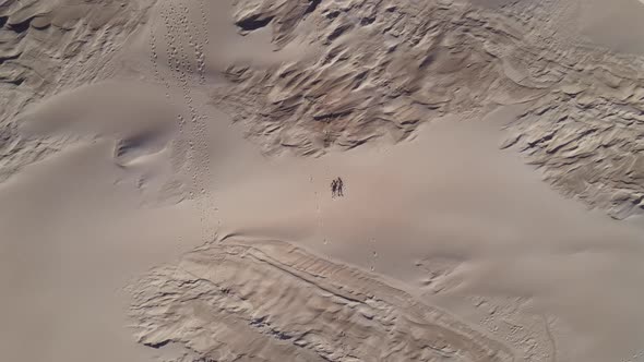 Aerial View of Drone Descending Towards Two People Laying on Sand