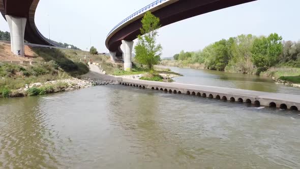 Aerial Low Flying Along Llobregat River Underneath Flyover Road In Catalonia alt