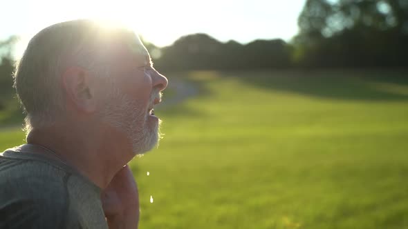 Slow motion sunny scene of man sneezing showing aerosol using water hose. alt