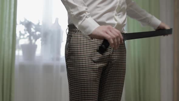 Groom Wears a Belt. Man in White Shirt Puts Belt on His Pants in Wedding Morning alt